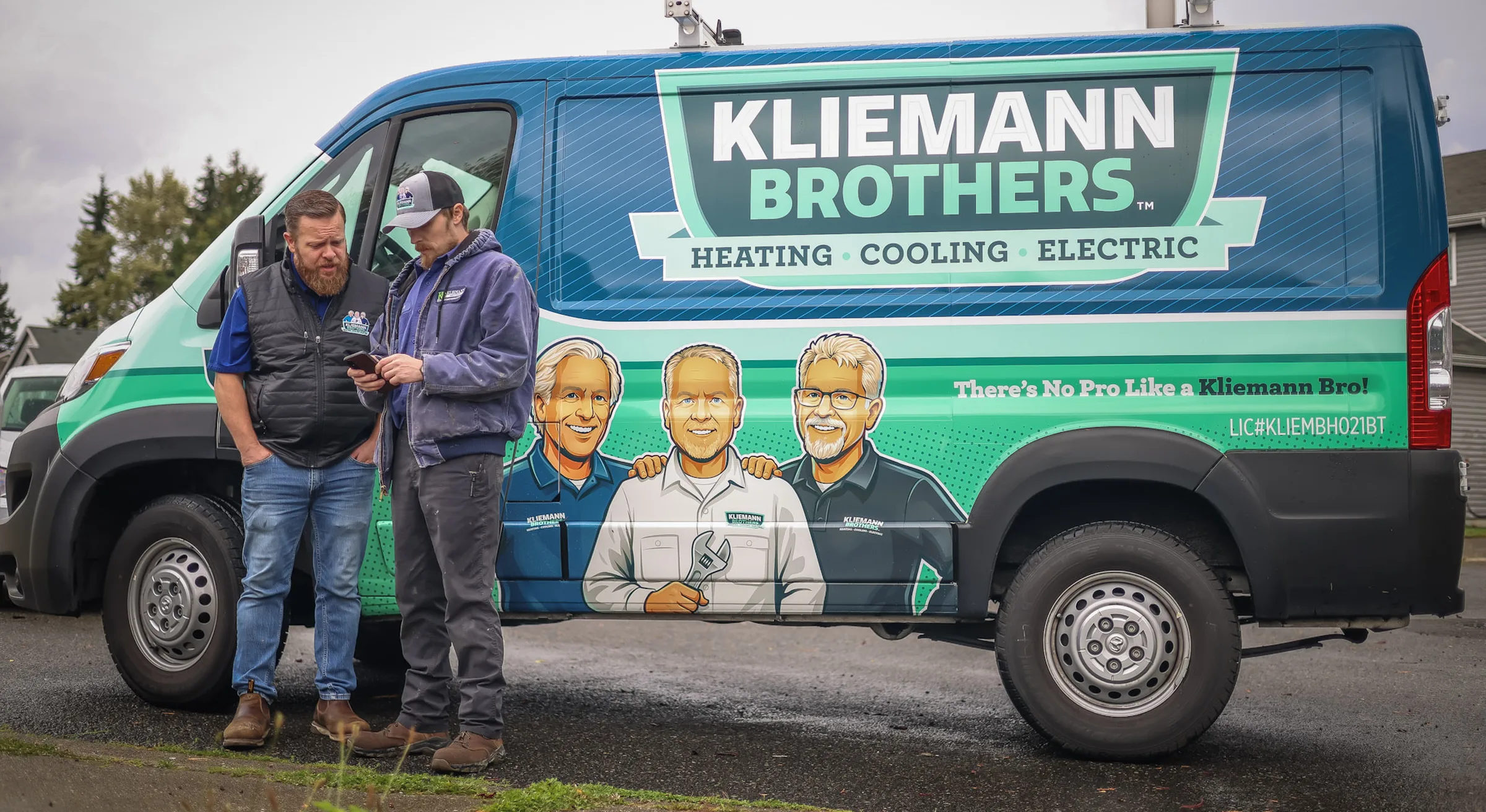 Two Kliemann Brothers technicians beside a branded service van showing the Kliemann Brothers Heating, Cooling and Electric wrap