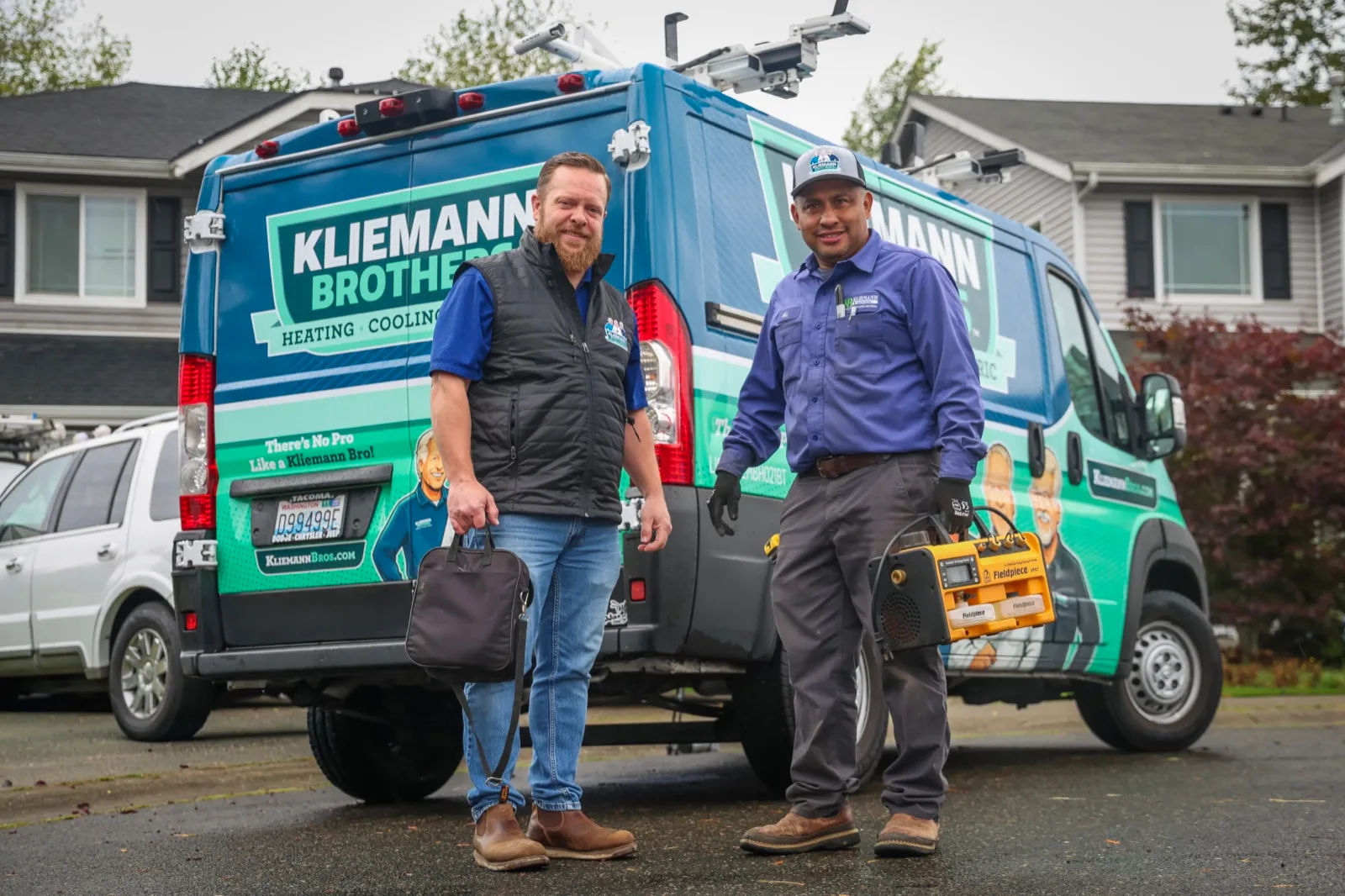 Two Kliemann Brothers technicians with their tools in front of a company van