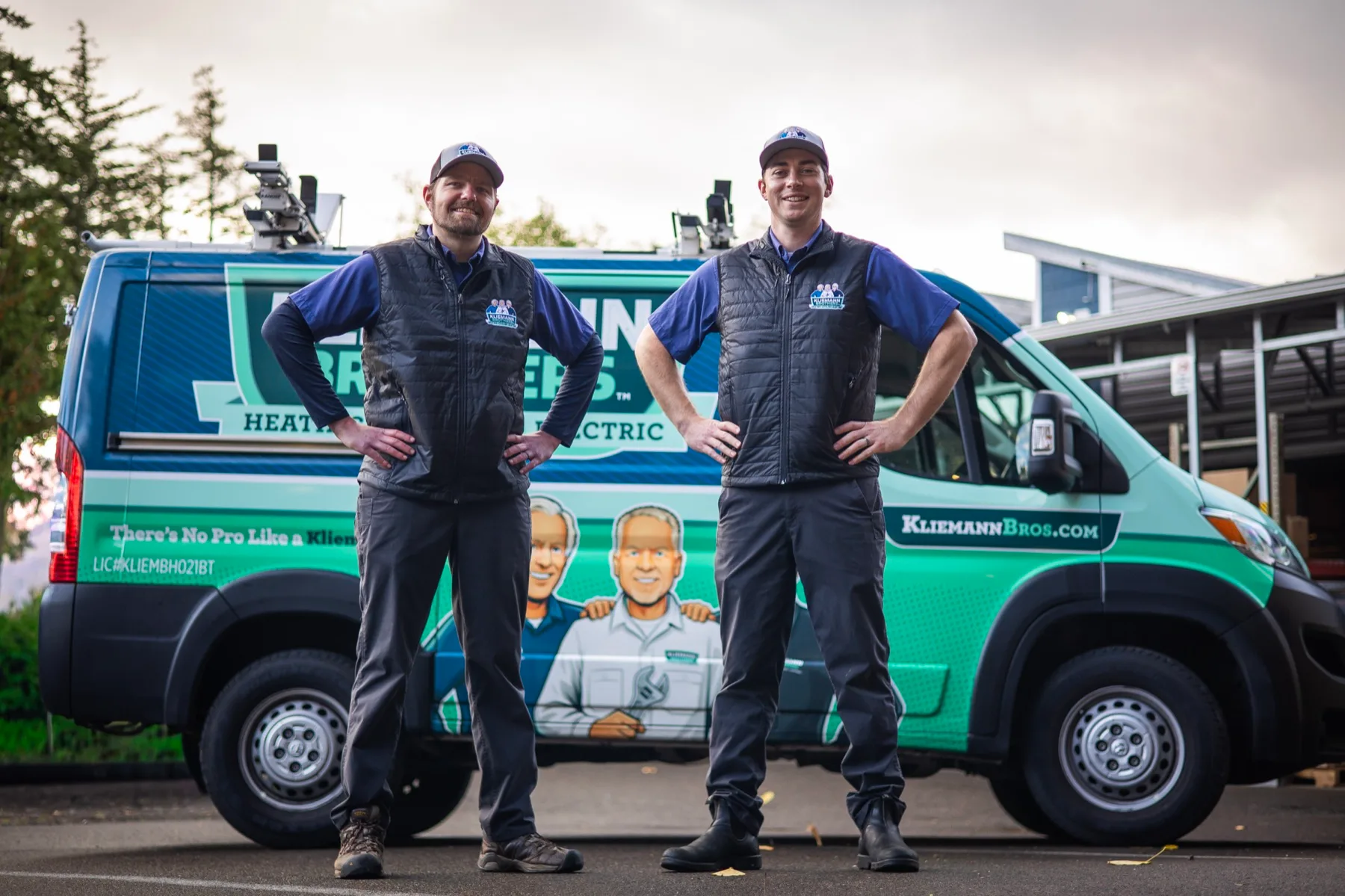 Two Kliemann Brothers technicians smiling in front of a company van