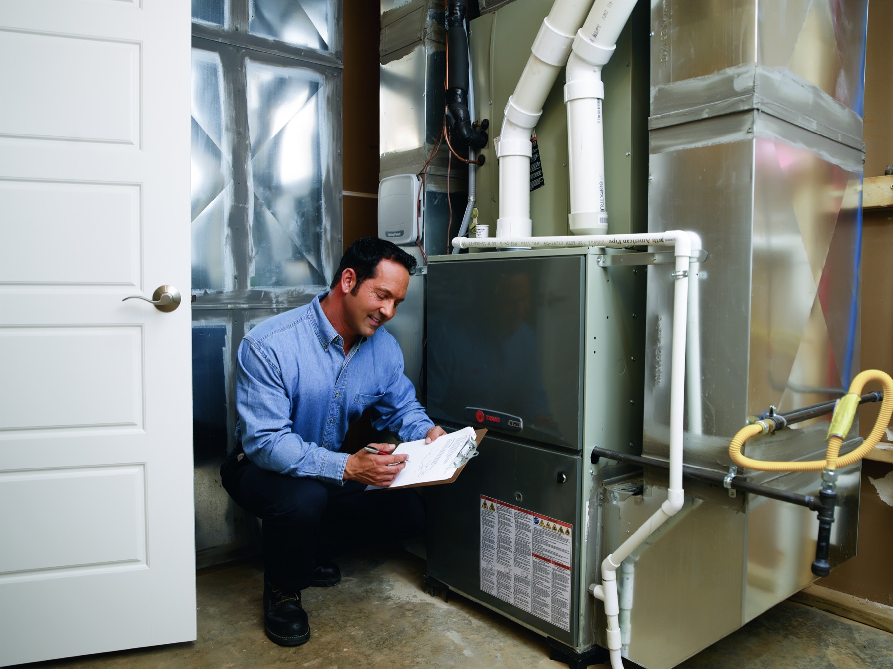 A Kliemann Brothers technician servicing an outdoor heat pump unit