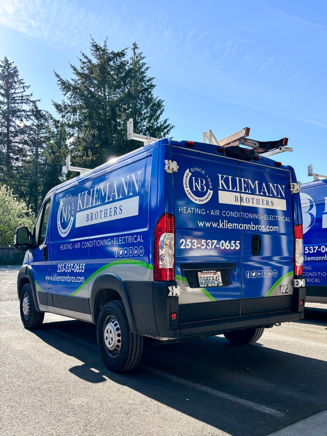 A Kliemann Brothers service van parked on a tree-lined Tacoma street