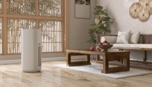 A modern living room with a wooden coffee table, a sofa, a bowl of apples, a bonsai tree, and an air purifier on a polished wooden floor near large windows.