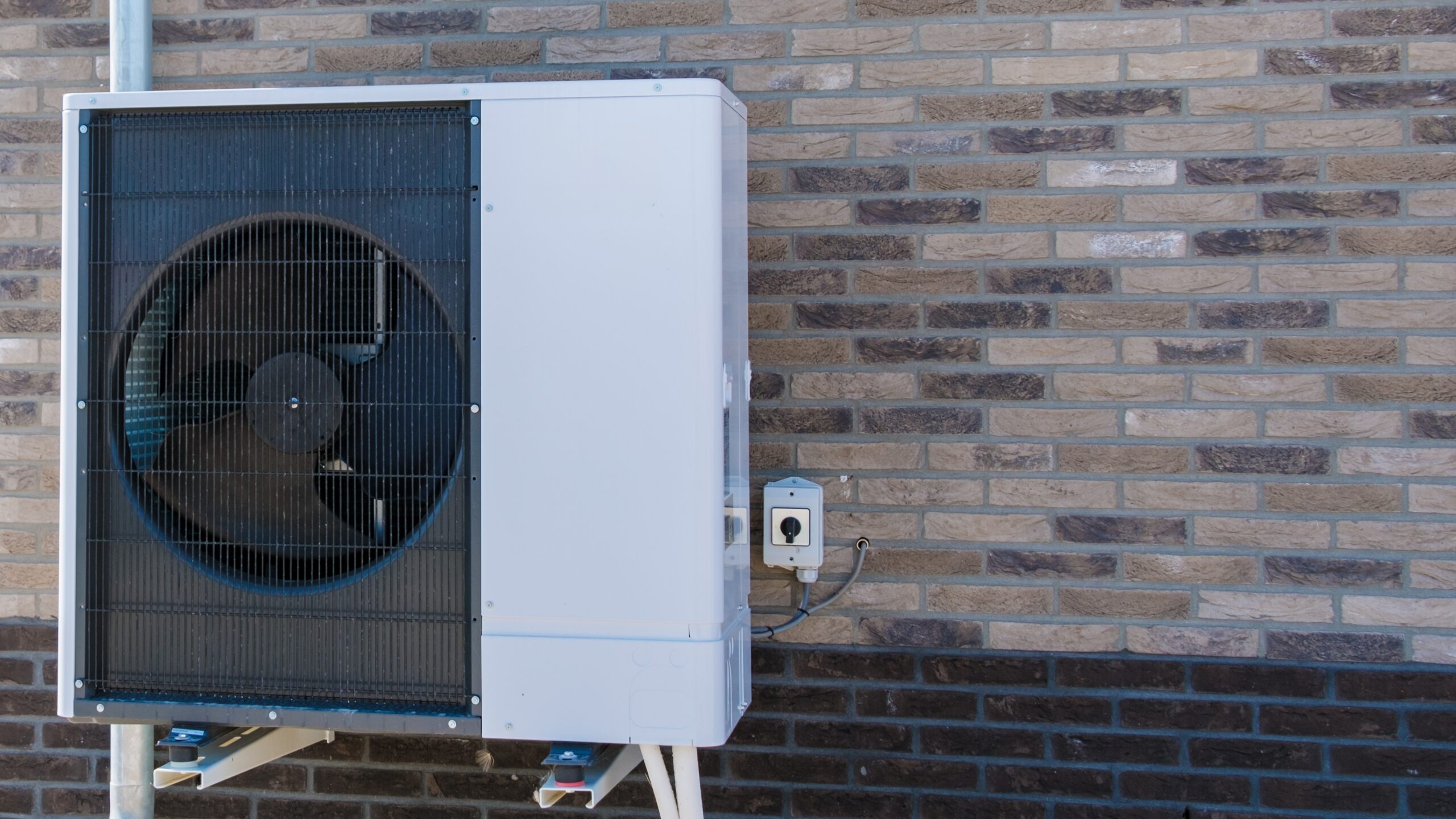 An,Air,Source,Heat,Pump,Is,Mounted,On,A,Brick large heat pump