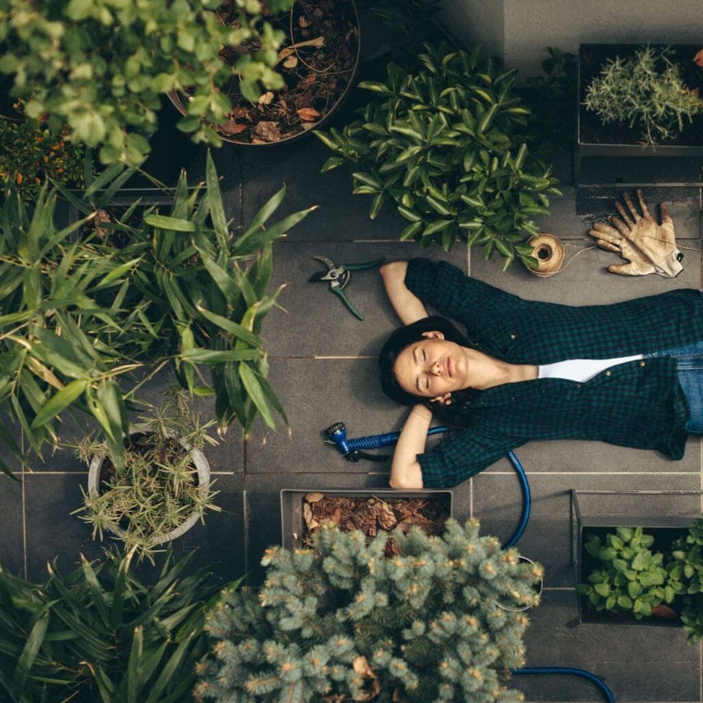 Woman reclining among house plants in home with clean air.